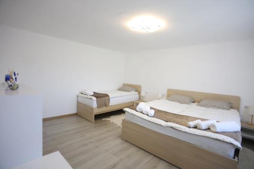 2 łóżka w pokoju z białymi ścianami i drewnianą podłogą w obiekcie Apartment Sončni Gaj w Ptuju