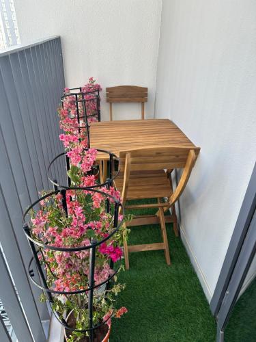 a small balcony with a table and chairs and flowers at WelcomeHome Apartments Aljada in Sharjah