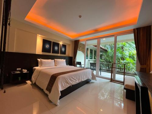 um quarto com uma cama grande e uma varanda em R-Mar Resort and Spa - SHA Plus em Praia de Patong