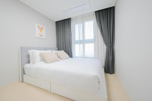 a white bedroom with a white bed and a window at E7 YANGYANG JUKDO in Yangyang
