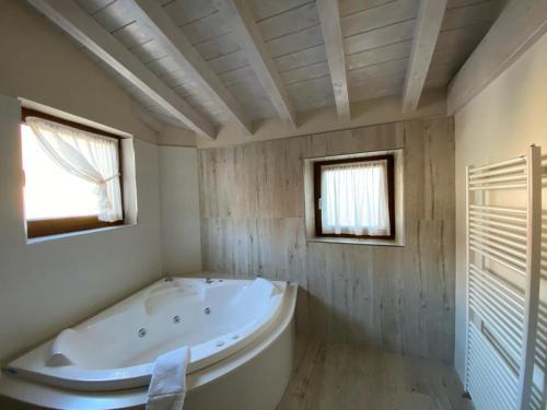 La salle de bains est pourvue d'une grande baignoire et de 2 fenêtres. dans l'établissement Picos de Europa Suites and Rooms, à Turieno