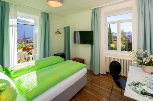 1 dormitorio con cama verde y balcón en Hotel Garni dei fiori, en Ascona