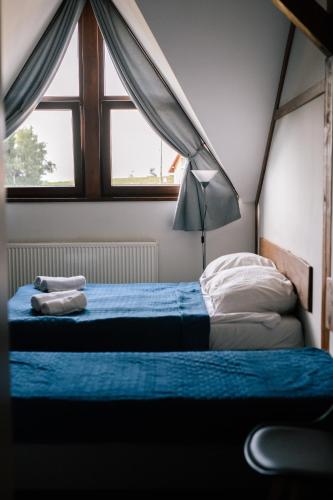 a bedroom with a bed with blue sheets and a window at Pod Sową in Sokolec
