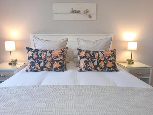 ein Schlafzimmer mit einem weißen Bett mit Kissen und 2 Lampen in der Unterkunft Willows Garden Cottage in Pretoria