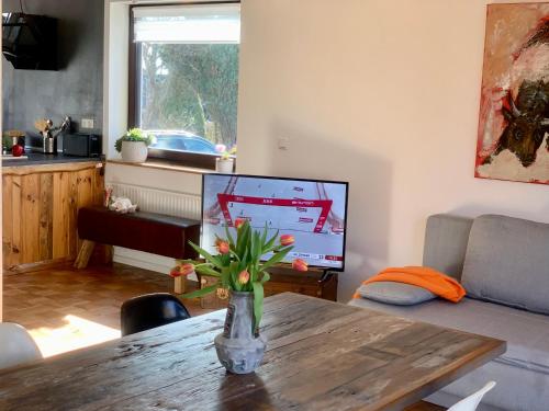 a living room with a vase on a table with a television at Casa Marcu Wohnung 2 EG in Landkirchen