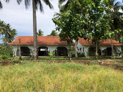 una casa bianca con tetto rosso e palme di Rumah Markisa Batukaras a Batukaras