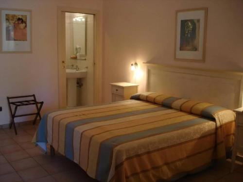 a bedroom with a bed and a bathroom with a sink at Borghetto Beach Club Resort in Capo Rizzuto