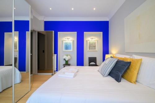 a bedroom with a large white bed with blue walls at Le COQ Impérial - Parking - Spacieux in Menton