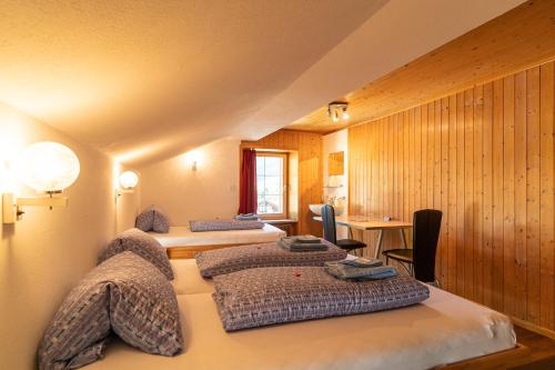 Cette chambre comprend 3 lits, une table et un bureau. dans l'établissement Gasthaus Edelweiss, à Vals