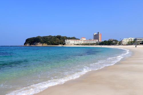 a beach with buildings in the background at Shiraraso Grand Hotel in Shirahama