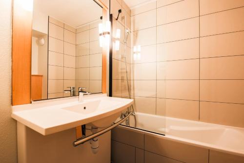 a bathroom with a sink and a mirror and a tub at easyHotel Nice Old Town in Nice