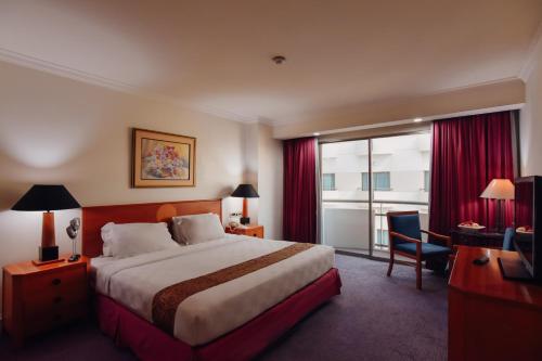 a hotel room with a large bed and a window at Surabaya Suites Hotel Powered by Archipelago in Surabaya