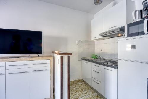 a kitchen with white cabinets and a flat screen tv at Apartment Riva 1001 in Rabac
