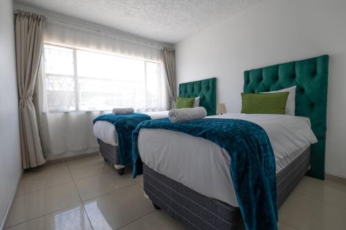 Un dormitorio con dos camas con cabeceros verdes y una ventana. en Safi Classic 3 bedroom Apartment 4, en East London