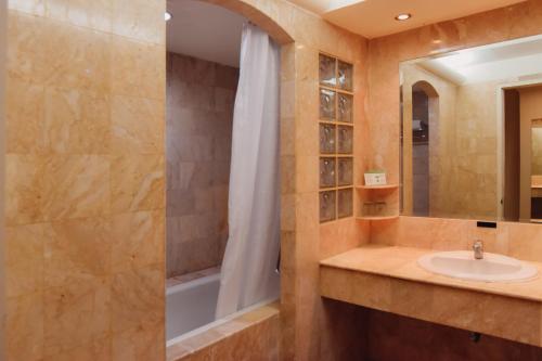 Surabaya Suites Hotel Powered by Archipelago في سورابايا: حمام مع حوض ودش
