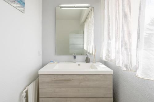 een badkamer met een witte wastafel en een spiegel bij Appartement Le Croas Men in Douarnenez