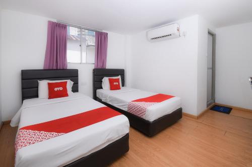 um quarto com duas camas com lençóis vermelhos e brancos em OYO 90089 N H Inn em Rumah Imba