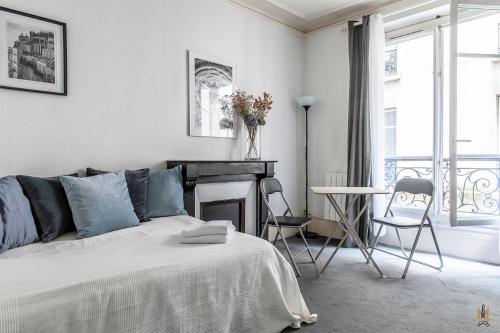 a white bedroom with a bed and a fireplace at Montmartre Apartments - Degas in Paris