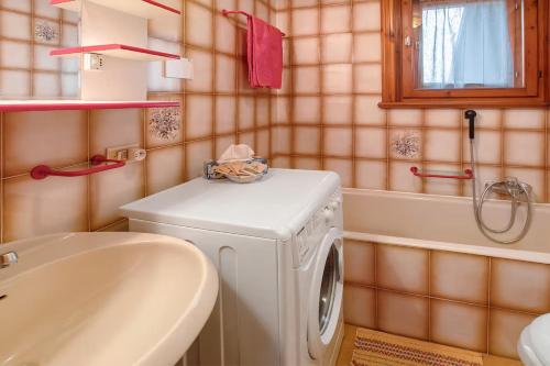 uma casa de banho com uma máquina de lavar roupa e um lavatório em Baita Florin em Livigno