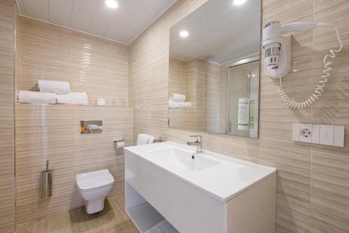 uma casa de banho com um lavatório branco e um WC. em Hotel Gran Sol em San Antonio