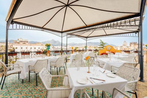 a restaurant with white tables and chairs and umbrellas at Eurostars Centrale Palace Hotel in Palermo