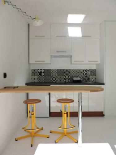 une cuisine avec une table et deux tabourets dans l'établissement 100 m de la plage, maison de vacances cœur de St Gilles, à Saint-Gilles-Croix-de-Vie