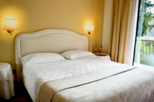 a white bed in a bedroom with a window at Admiral Hotel Villa Erme in Desenzano del Garda