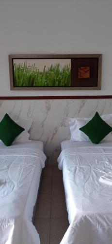 two white beds with green pillows in a room at khrisna Bungalow Tulamben in Kubu
