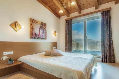a bedroom with a bed and a large window at Exclusive Panorama Spa Suiten DAS SCHILLER in Bad Gastein