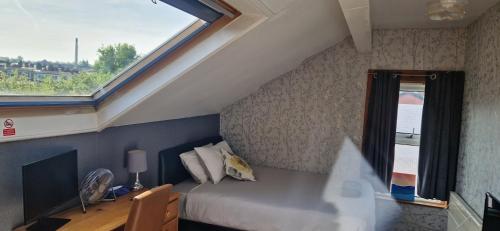 a bedroom with a bed and a window and a desk at KAYUMBA Properties LTD in Leeds