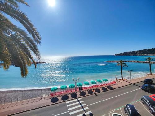 eine Straße mit einem Strand mit Sonnenschirmen und dem Meer in der Unterkunft Le COQ Ligures - Garage - AC - Seafront - WiFi in Roquebrune-Cap-Martin