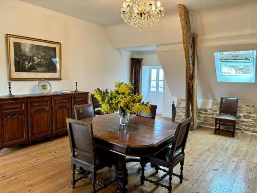 une salle à manger avec une table, des chaises et un lustre dans l'établissement Château de la Pervenchère gîte des Cavaliers, à Casson