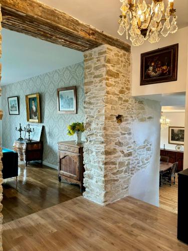 Elle comprend un salon doté d'un mur en pierre et d'un lustre. dans l'établissement Château de la Pervenchère gîte des Cavaliers, à Casson