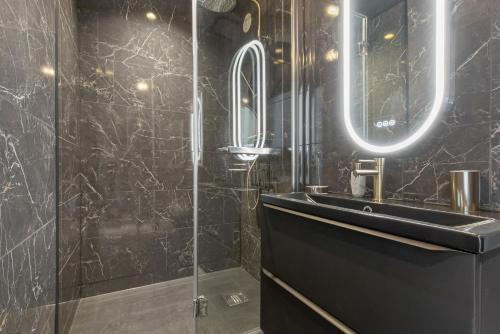 une salle de bain noire avec un lavabo et un miroir dans l'établissement Coco beach Heliopolis, au Cap d'Agde