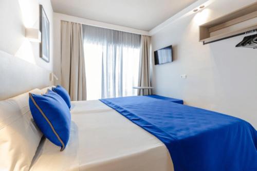 a white bed with blue pillows in a bedroom at Cabot Playa Grande - Adults Only in Playa de Palma