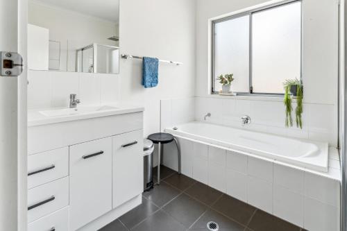 ein weißes Badezimmer mit einer Badewanne und einem Waschbecken in der Unterkunft Enfield Executive in Gepps Cross