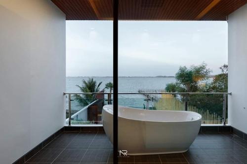 a bath tub in a bathroom with a view of the ocean at Touchwarin kohyor pool villa ธัชวารินเกาะยอพูลวิลล่า in Songkhla