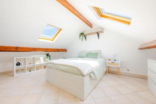 - une chambre blanche avec un lit et des lucarnes dans l'établissement Le Cocon Proche Paris Stellantis, à Poissy