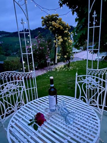 a white table with a bottle of wine and a flower on it at Residence delle Rose in Barolo