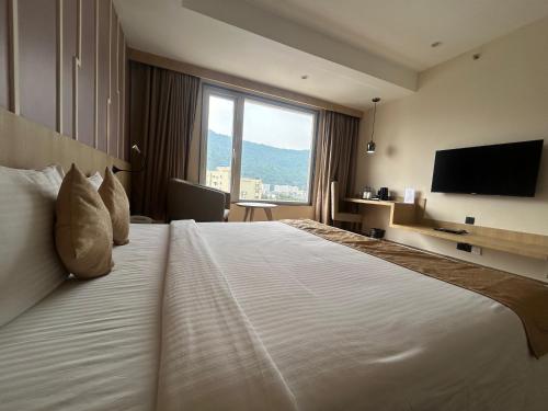 a hotel room with a large bed and a television at Sachika Hotels, Guwahati in Guwahati