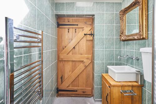 a bathroom with a wooden door and a sink at Quaint, rustic cabin with period features, stunning views & hot tub in Llangadog