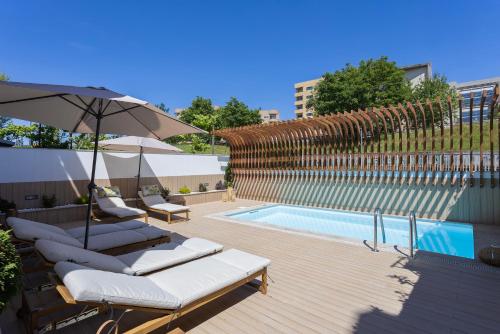 a pool with lounge chairs and an umbrella next to a swimming pool at Levada Charming Houses (Refúgio) - 1 min Metro in Rio Tinto