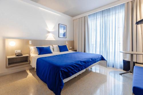 a bedroom with a blue bed and a large window at Cabot Playa Grande - Adults Only in Playa de Palma