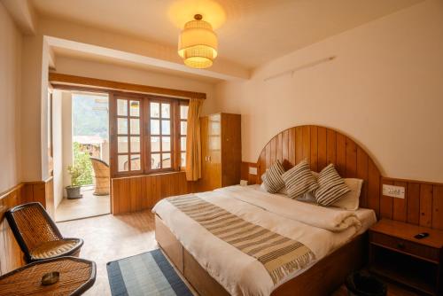ein Schlafzimmer mit einem großen Bett und einem Fenster in der Unterkunft Drifters Inn - The Hidden Tribe in Manali
