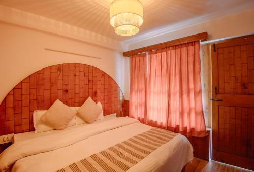 a bedroom with a large bed and a window at Drifters Inn - The Hidden Tribe in Manāli