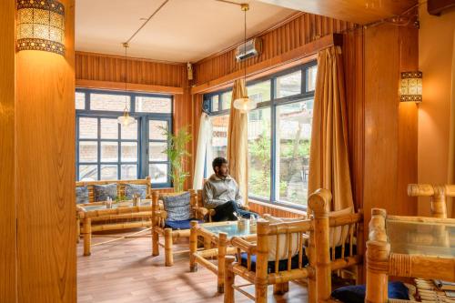 a man sitting in a room with a window at Drifters Inn - The Hidden Tribe in Manāli