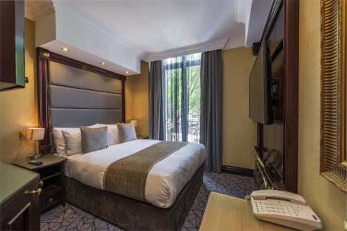 a hotel room with a bed and a desk with a computer at Hyde Park International in London