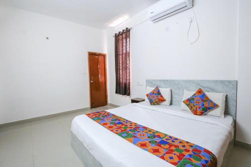 a bedroom with a large white bed with colorful pillows at FabExpress KP Suites Villas in Turkapally