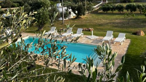 a group of lounge chairs and a swimming pool at Trullo Nadia Ostuni in Ostuni