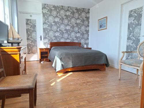 a bedroom with a bed and a table and a chair at La fleur du soleil in Trouville-sur-Mer